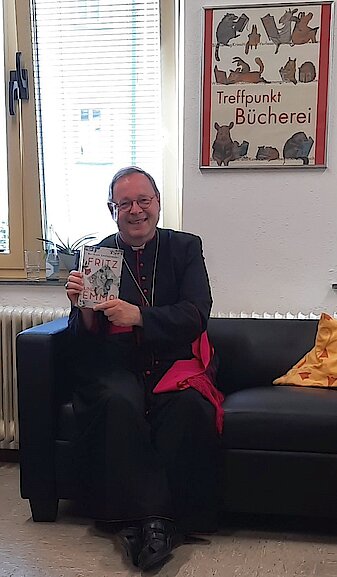 Der Bischof zeigt das ihm empfohlene Buch "Fritz und Emma"